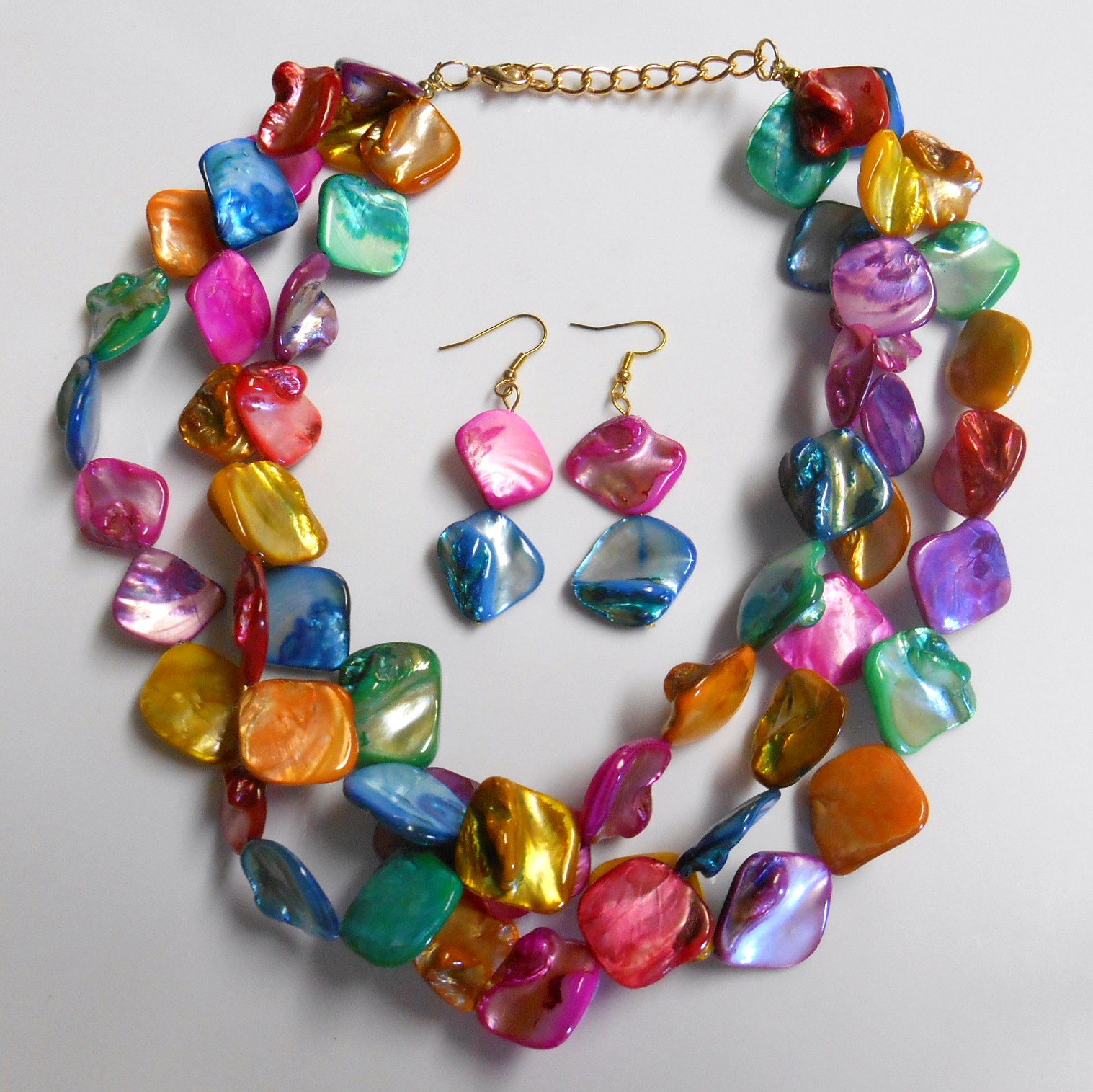 Three strands of vibrant rainbow multi color shells make up this unique necklace. The matching hook dangle earrings are made of the same pink and blue shells.