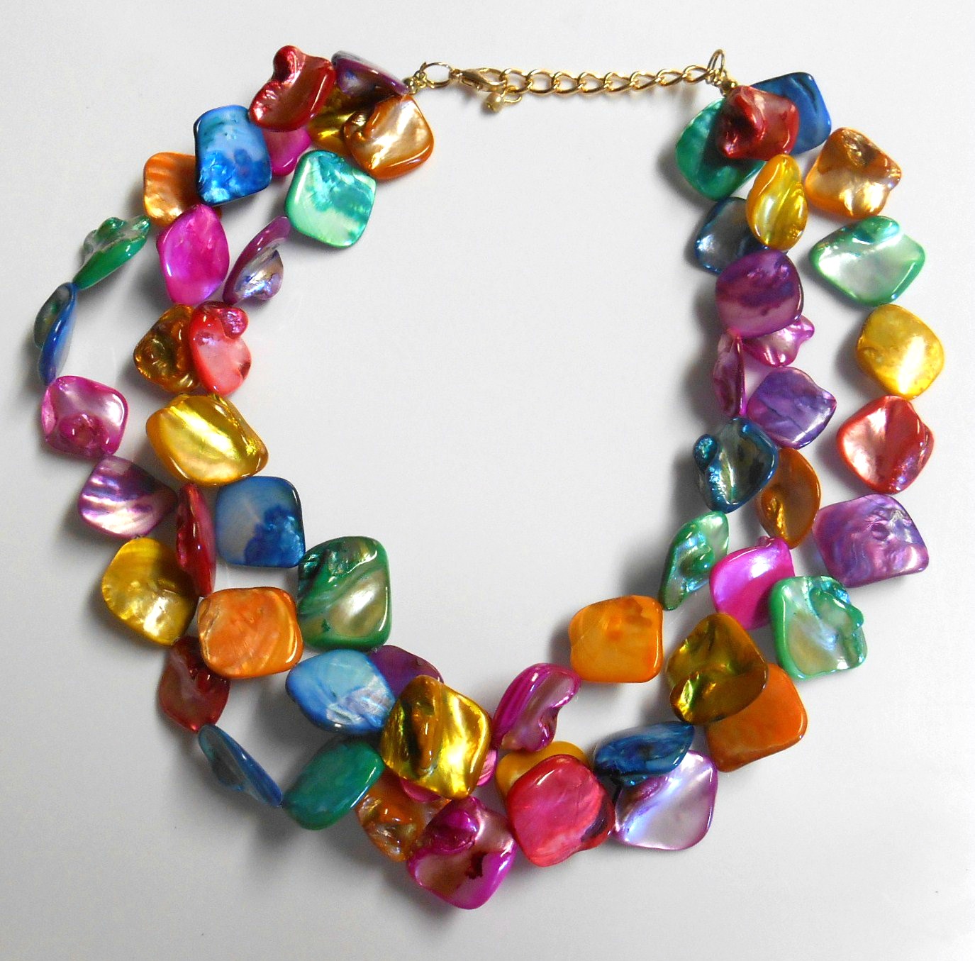 Three strands of vibrant rainbow multi color shells make up this unique necklace. The matching hook dangle earrings are made of the same pink and blue shells.