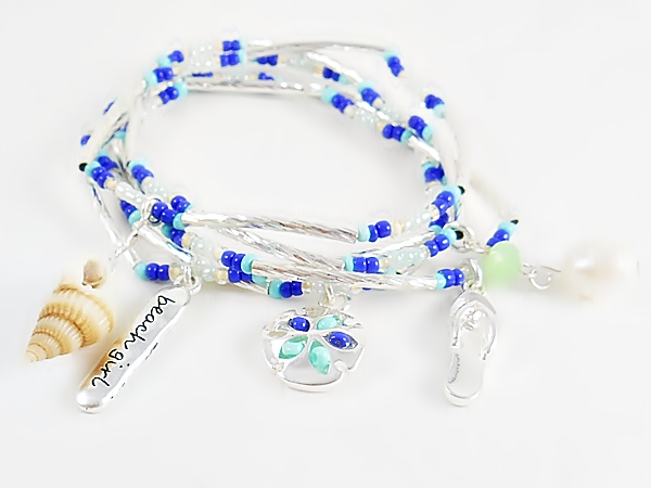 Set of 5 stretch bracelets with turquoise, blue and iridescent seed beads, silver tube beads and beach themed charms including a sand dollar, flip flop, sea shell, pearl bead, and beach girl.