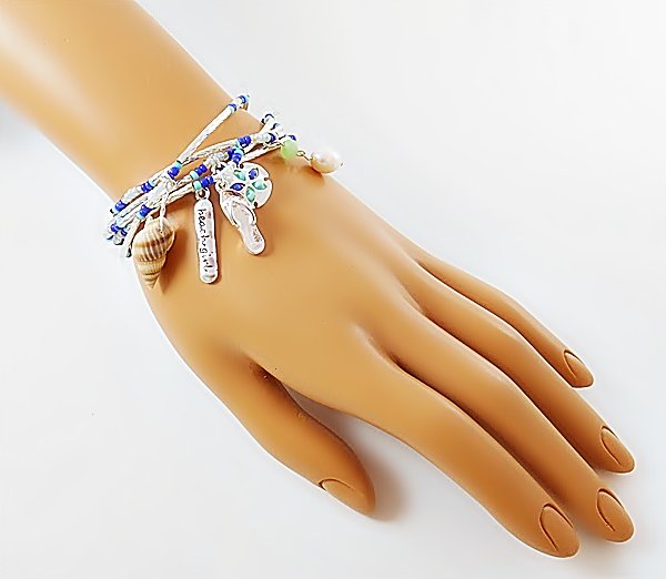 Set of 5 stretch bracelets with turquoise, blue and iridescent seed beads, silver tube beads and beach themed charms including a sand dollar, flip flop, sea shell, pearl bead, and beach girl.