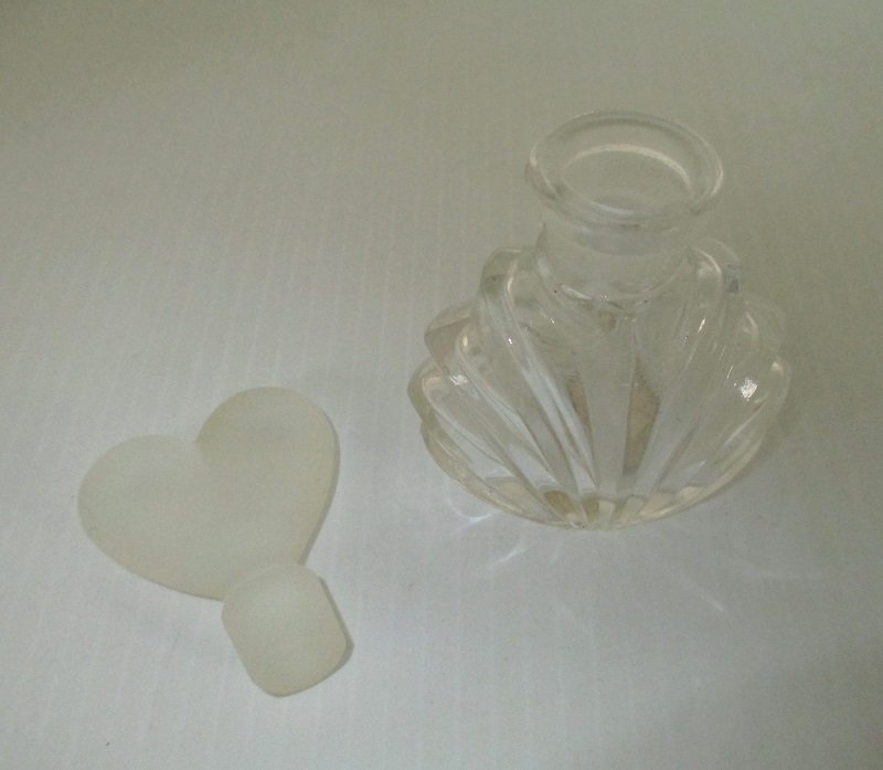 4.25 inch tall perfume bottle with I.W. Rice sticker on bottom. Frosted ground glass heart shaped stopper.  Unknown date. The bottle is empty.