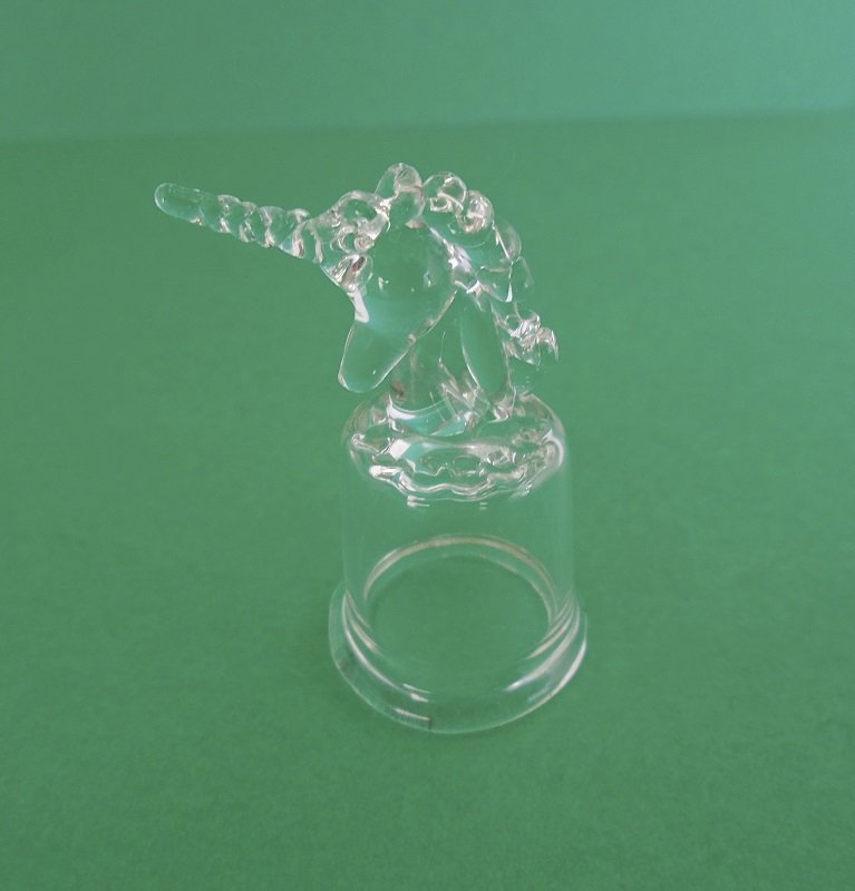 Clear glass thimble with the top in the shape of a unicorn. Stands 1.75 inches tall to the end of the horn. No markings, unknown date. Estate find.