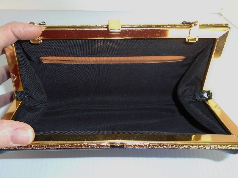 Inside Etienne Aigner vintage 1970s black clutch purse. Snake embossed with gold color hardware. Hide-a-way 5 inch drop chain strap.