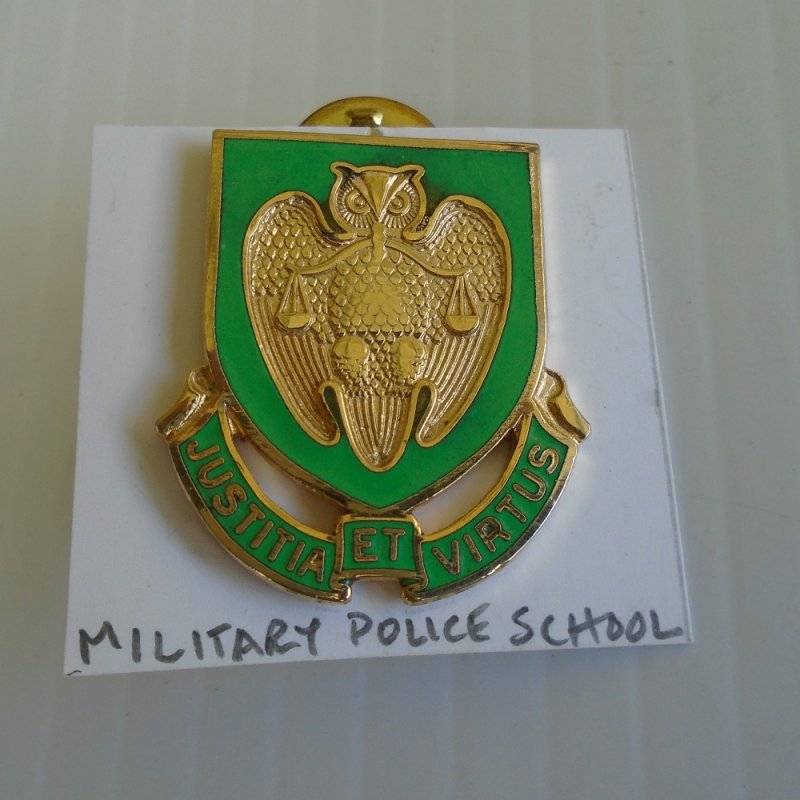 Insignia pin for U.S. Army Military Police School. Unknown age. Features an owl holding the 'scales of justice'. Worn on uniforms.
