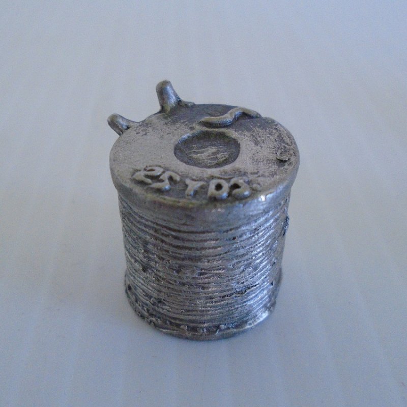 Collectible souvenir pewter thimble shaped like a spool of thread with needles sticking in the side. Unknown age. Most likely Nicholas Gish. 
