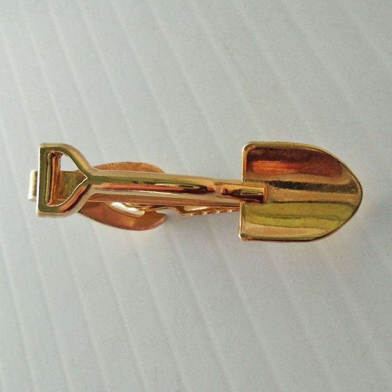 Gold colored tie clip featuring a shovel. Perfect for a construction worker, landscaper, gold miner. Unknown age, estate sale item.