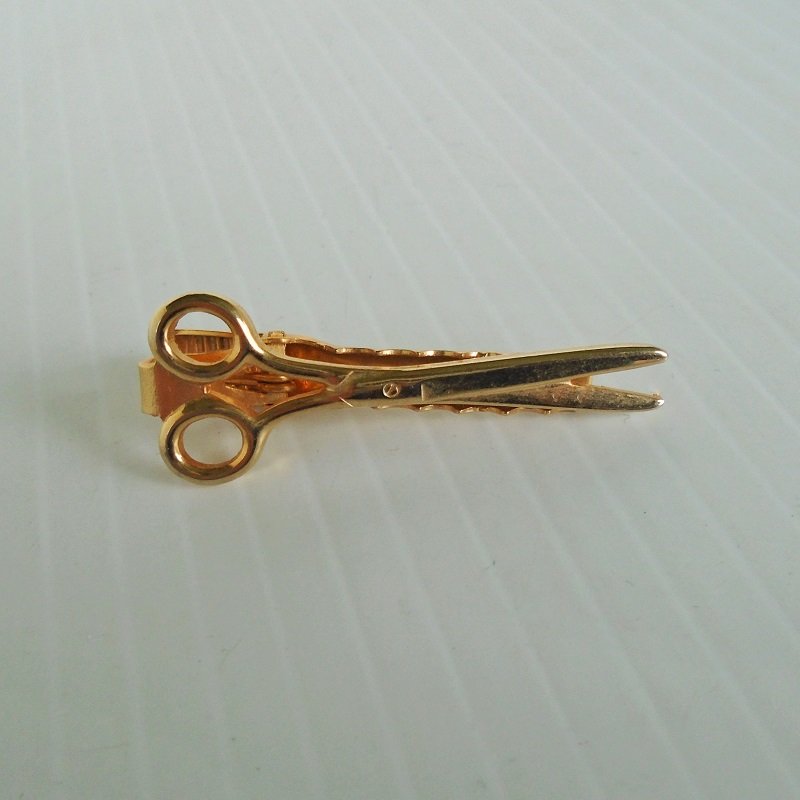 Vintage tie clip, gold in color. Measures 1.5 inches long. Great for a beautician, barber, or arts and crafts person. Stated to be from the 1980s.