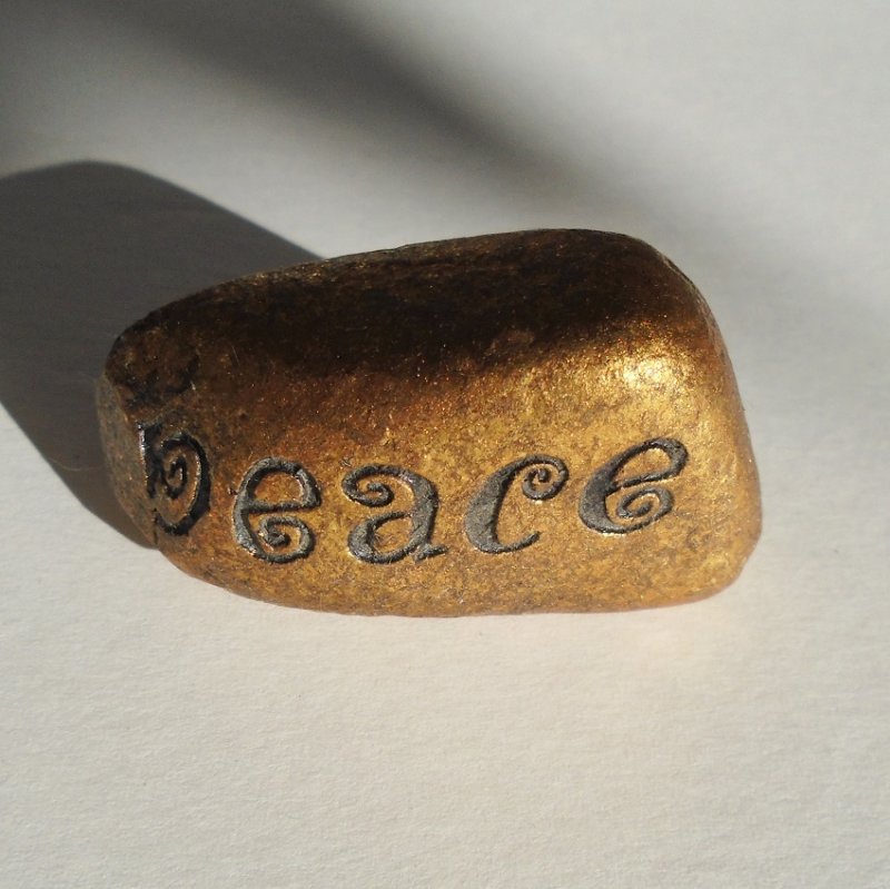 Peace rock, painted gold with the word 