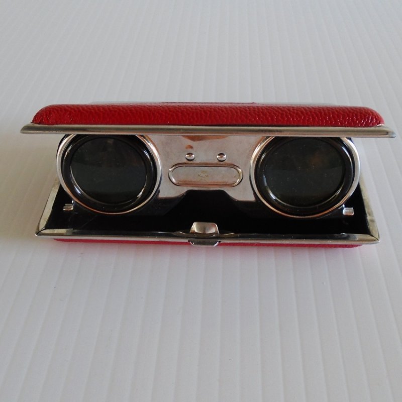 Folding Opera Glasses housed inside a chrome and red leather case. One piece unit from the 1960s. Has focusing ability. Estate find. 