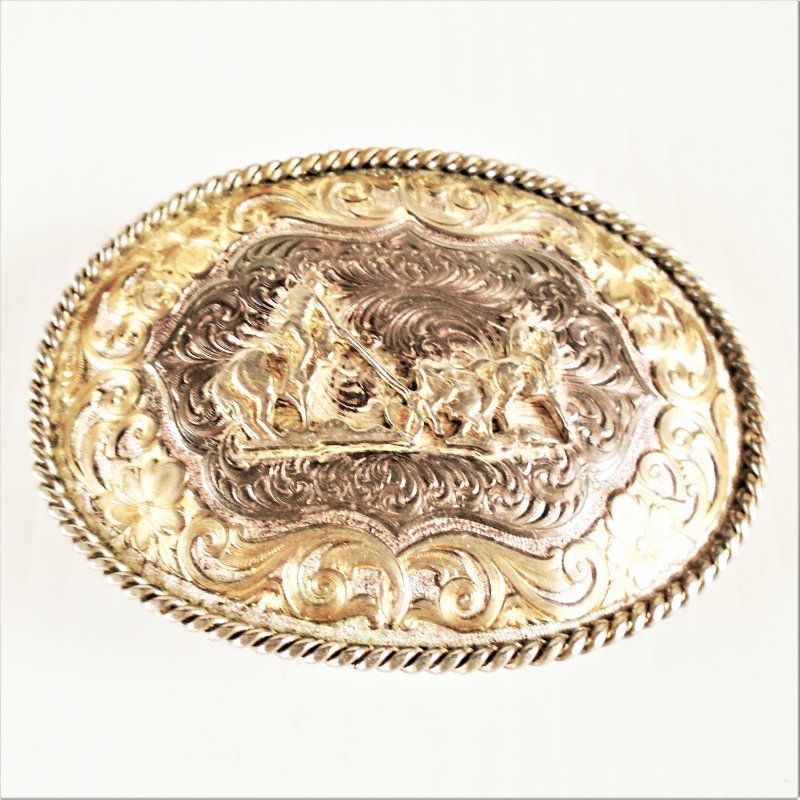 Montana Silversmiths rodeo themed silver plated belt buckle. Cowboy roping calf. Probably 1970s.
