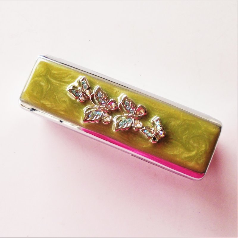 Lipstick case with rhinestone filled butterflies on enameled top. Hinged, has mirror and felt lining inside.