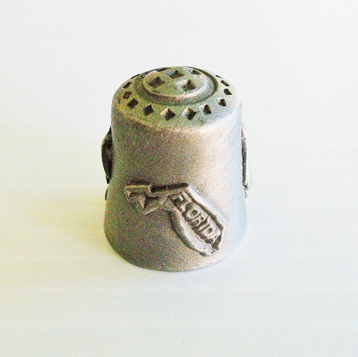 Collectible souvenir pewter thimble for the state of Florida. Signed Gish (for Nicholas Gish). 1 inch tall. Pelican, palm tree. Unknown age.