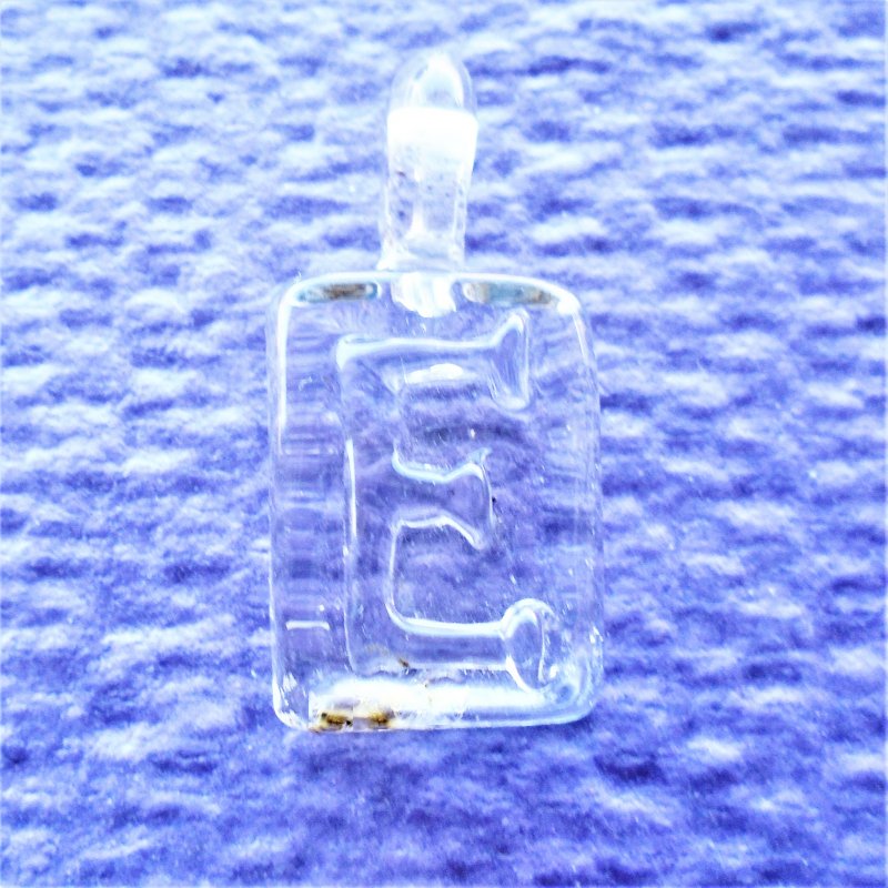 Letter E clear glass artwork pendant. Measures 1 by 3/4inches. Never worn.