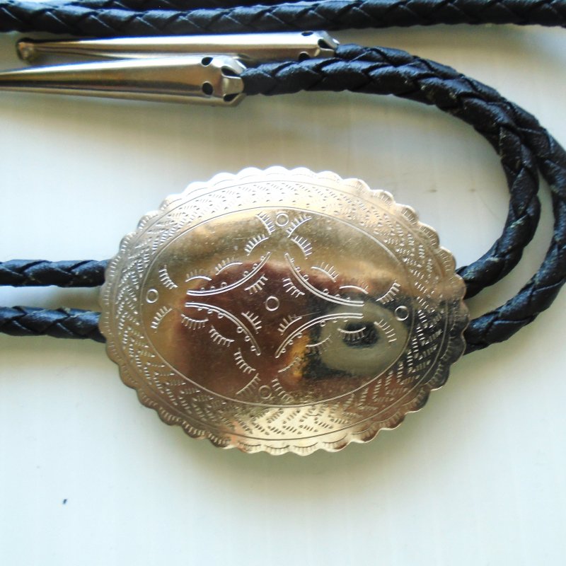 Silver oval disc measuring 1.5 by 2 inch bolo tie on a 36 inch cord.