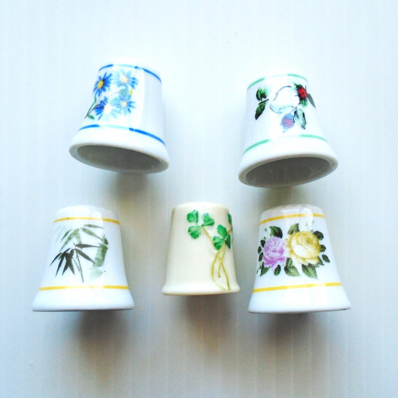 5 Collectible porcelain thimbles with floral themes.