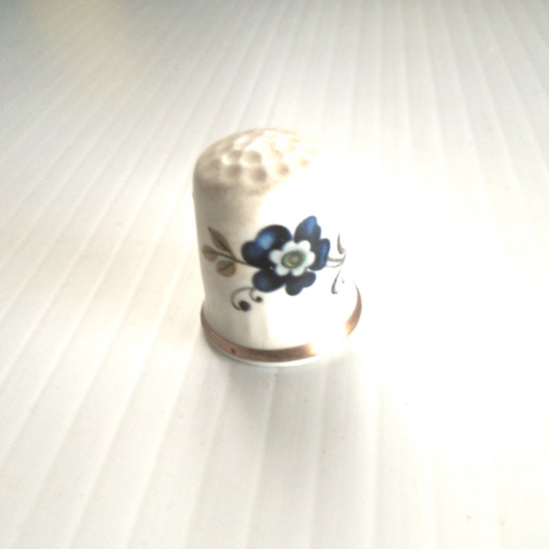 Vintage collectable thimble featuring a blue flower. Made of bone chine. Marked “Sanford, Made in England”.