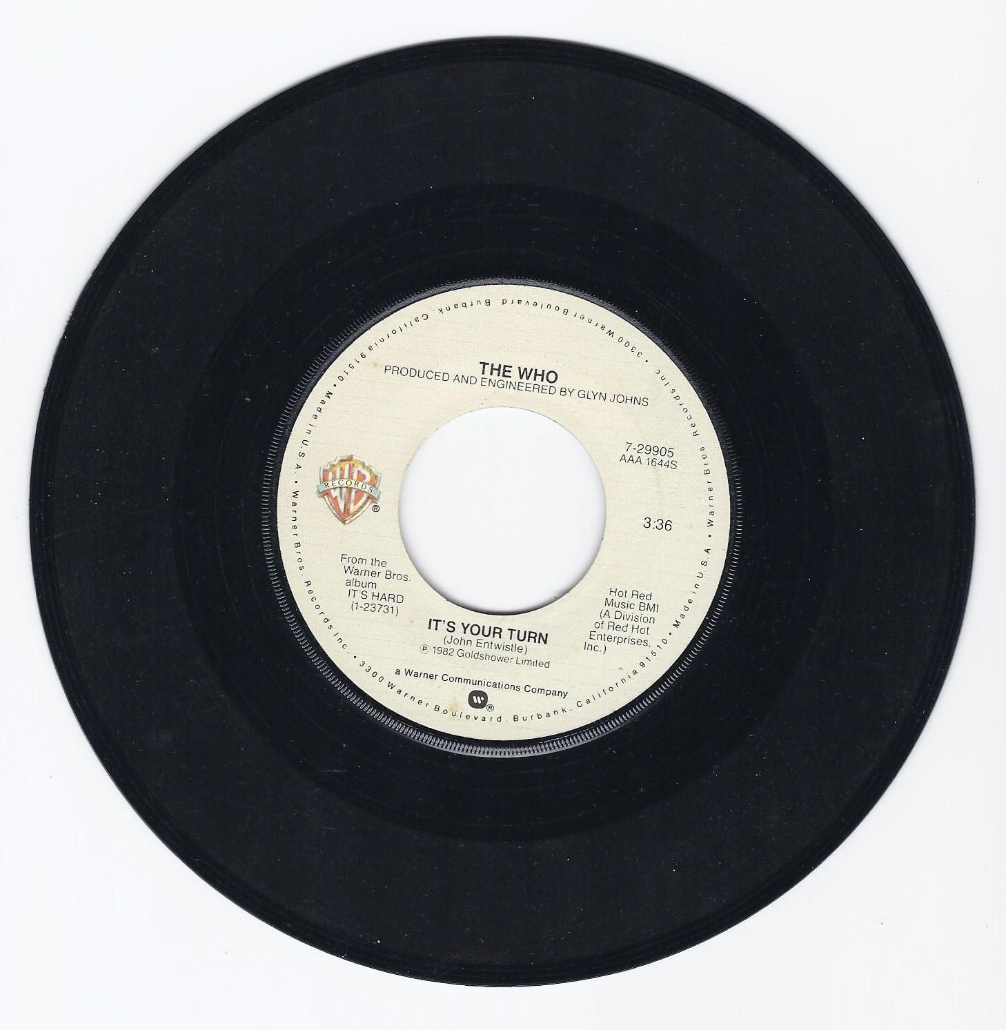 Close up view of the off-white Warner Bros. Records center label on the authentic 1982 vintage 7 inch 45 RPM vinyl record single It's Your Turn by The Who.