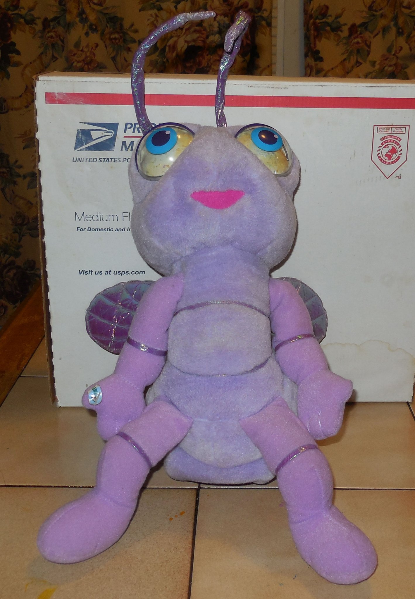 Front view of the 1998 Mattel A Bug's Life Dot talking plush toy showing her purple body, plastic eyes, and green leaf hairpiece.