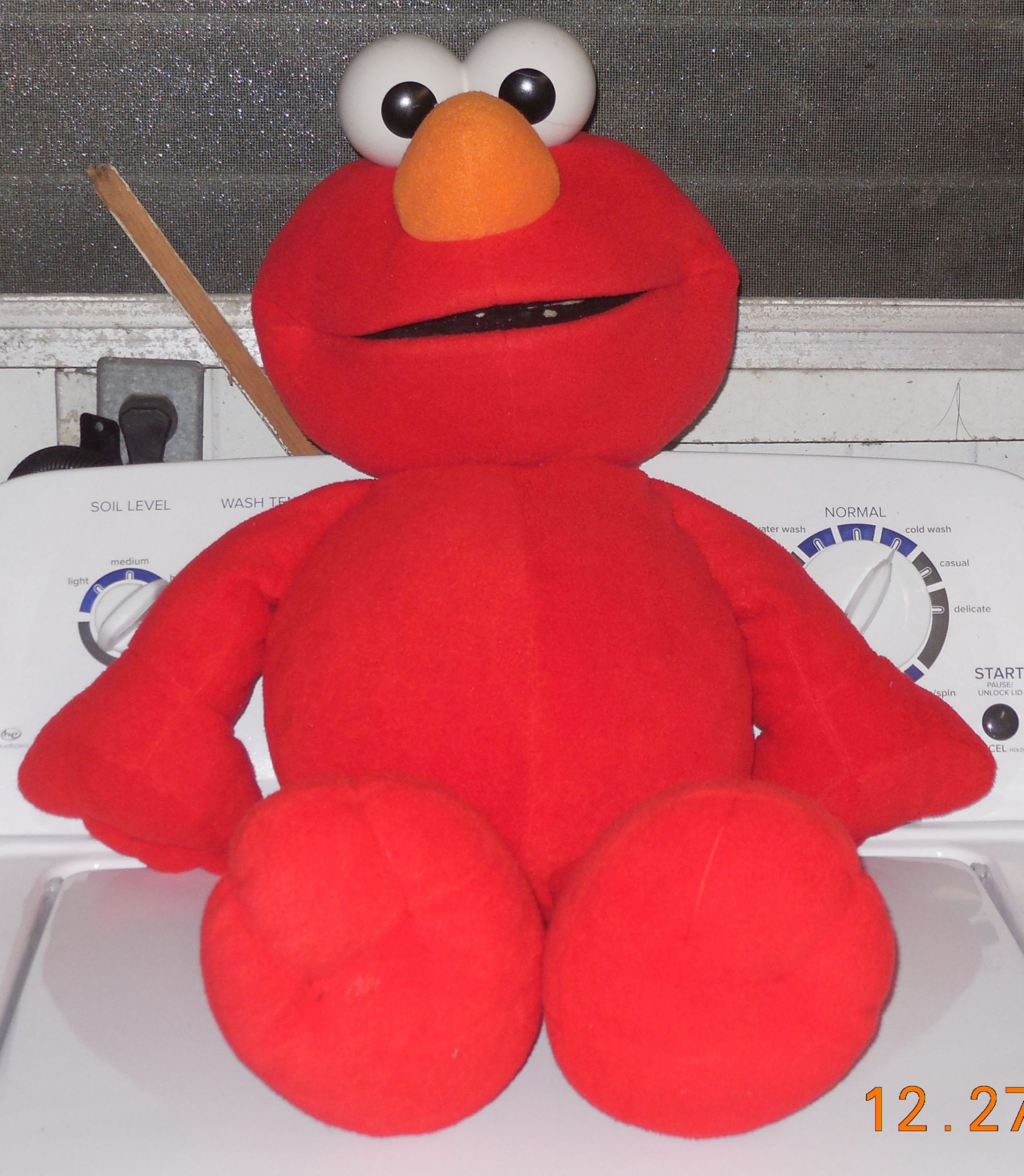 Front view of the large Sesame Street Elmo plush doll showing his shaggy red fur, white plastic eyes, and orange nose.